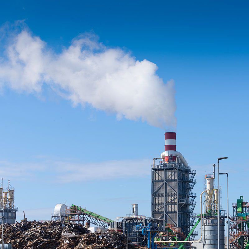 Industrial plant with smokestack and blue sky.