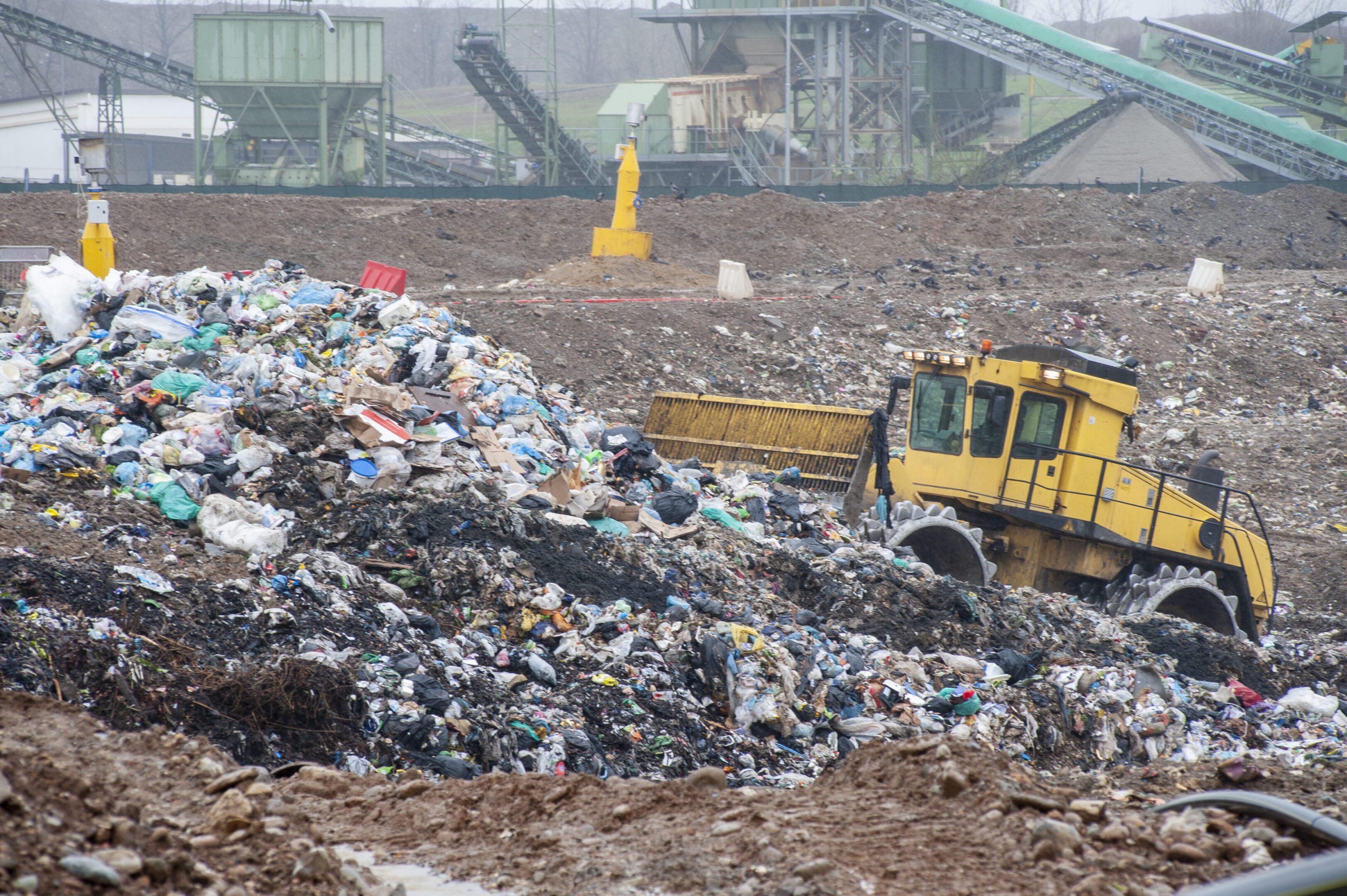 Municipal waste landfill. Municipal waste landfill. Workers with trucks and bulldozers at work in waste storage landfill.