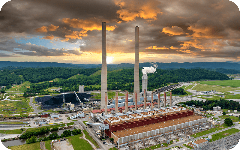 Power plant with smokestacks under dramatic sky.