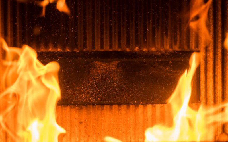 Flames engulf a dark, textured surface in intense heat.